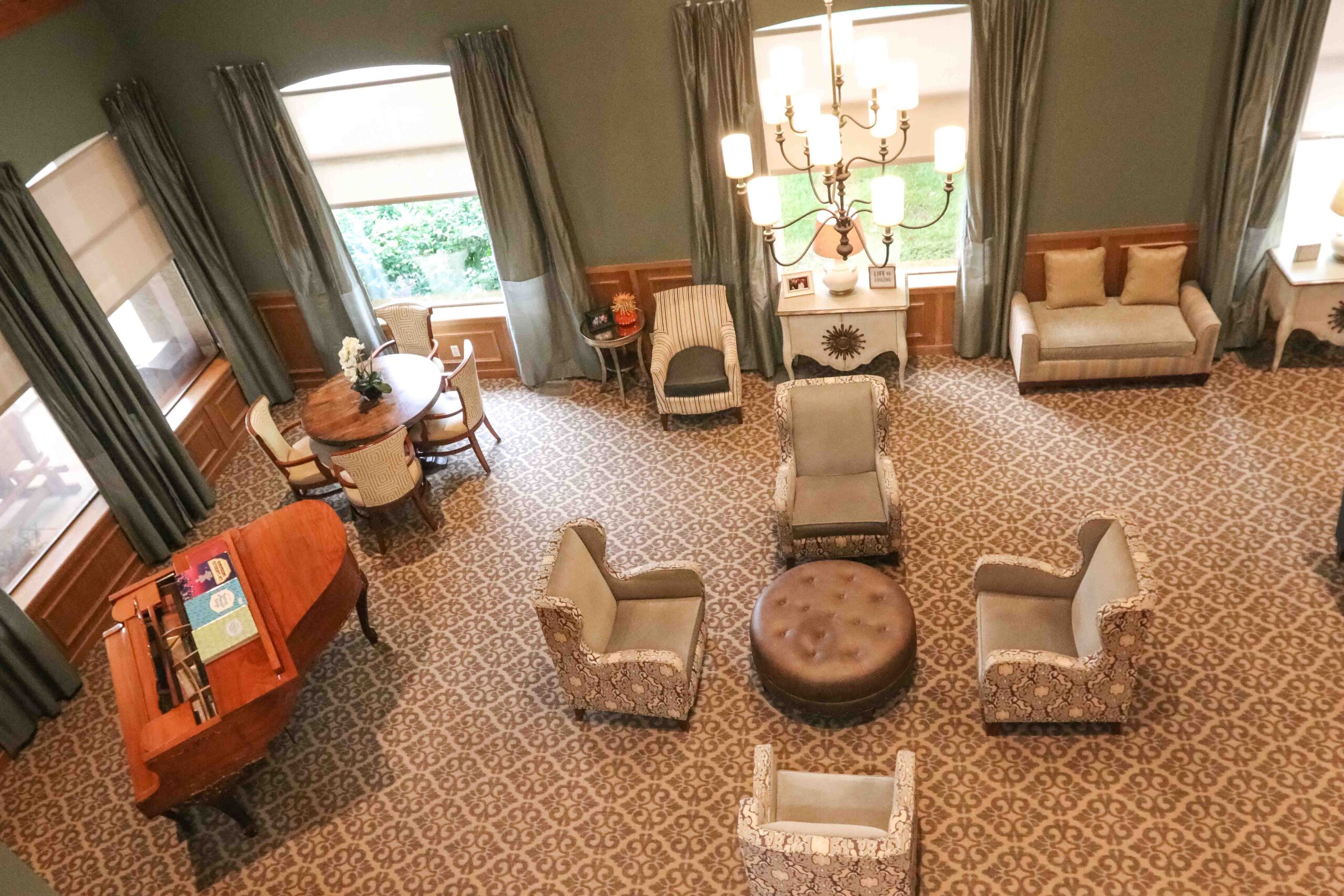Interior aerial image of the common room with plenty of comfortable seating and a baby grand piano at Sedgwick Plaza.