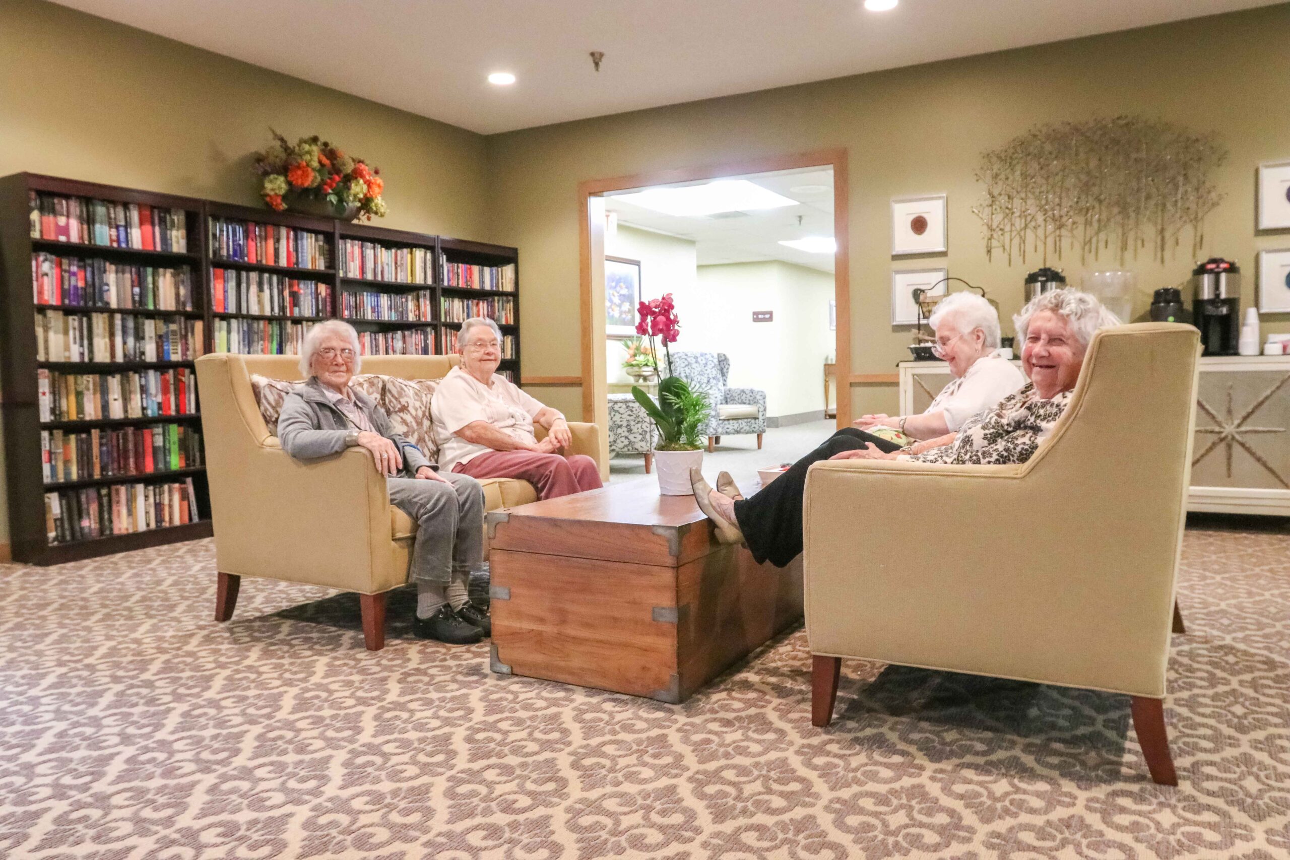Four residents socializing in the library at Sedgwick Plaza, a trusted choice for senior living.